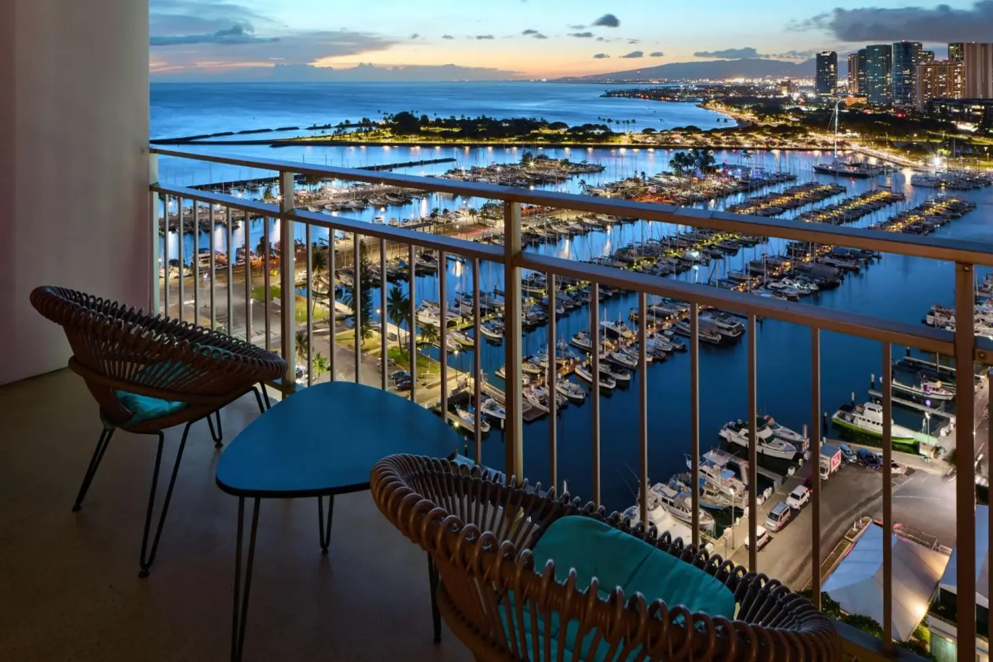 Balcony seating overlooking the marina and coastline at dusk at Ilikai Hotel.