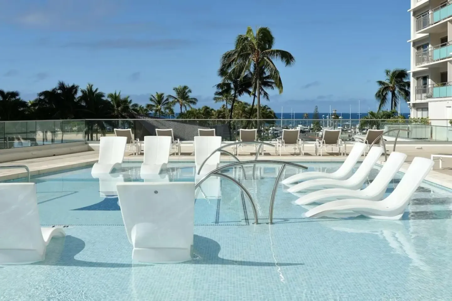 Pool with in-water lounge chairs and ocean beyond at Ilikai Hotel.