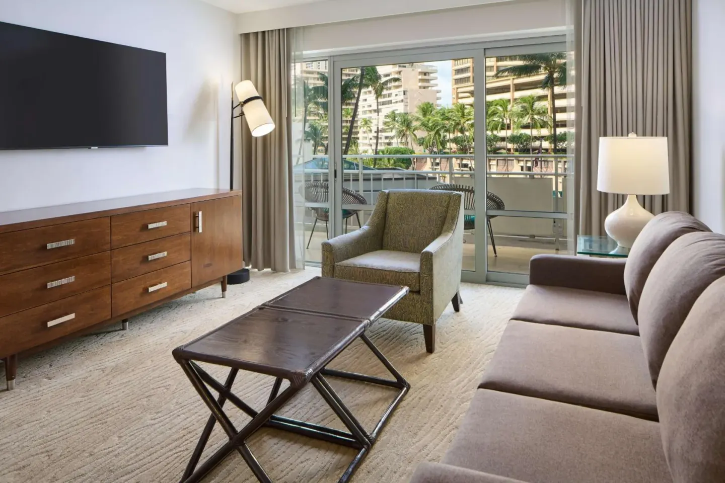 Suite living room with sofa, balcony doors, and palm views at Ilikai Hotel.