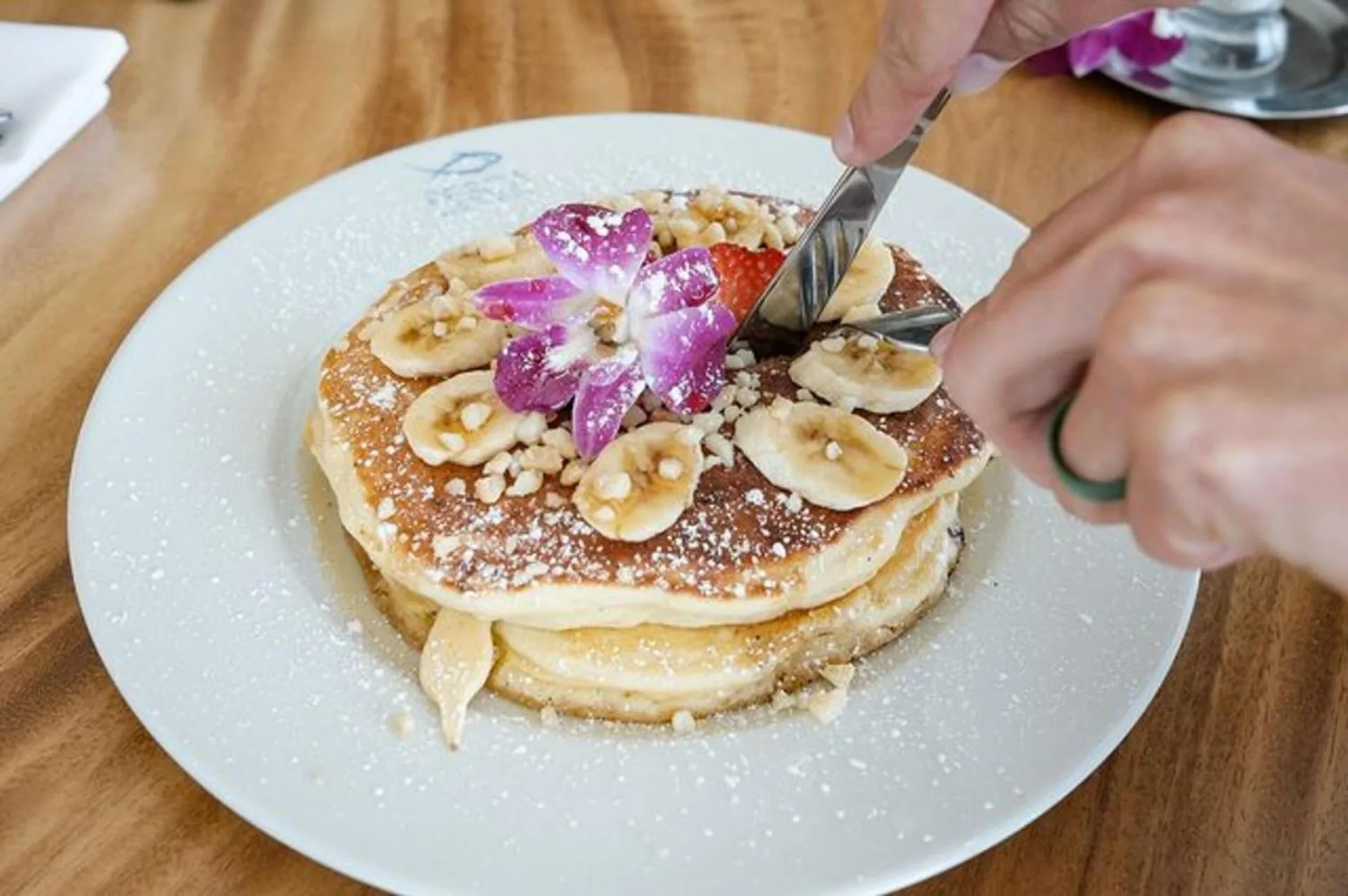 Banana-topped pancakes at Ilikai Hotel being cut with a fork and knife.