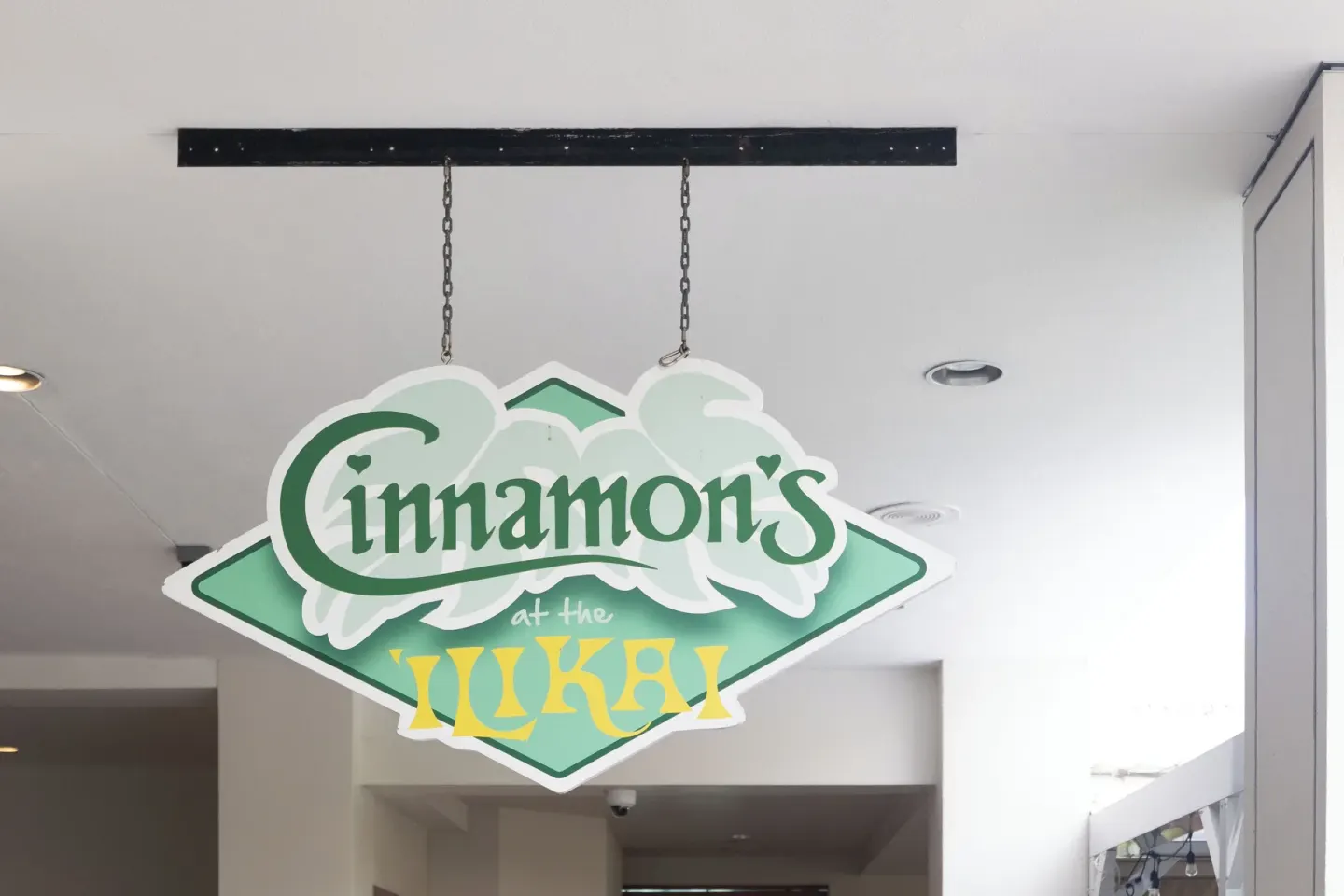 Hanging Cinnamon's sign in an interior walkway at Ilikai Hotel.