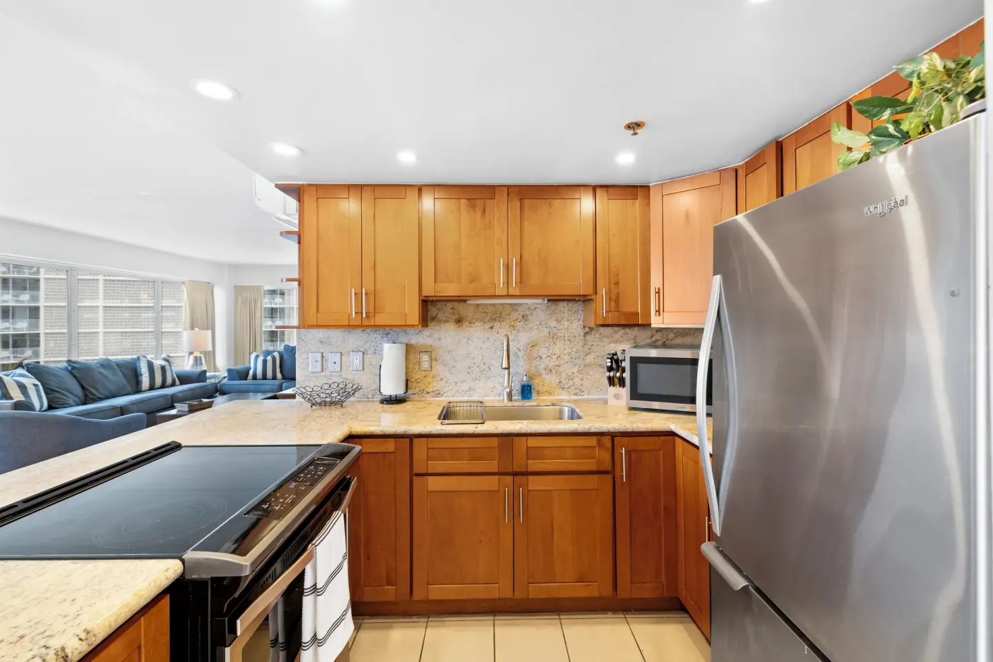 Kitchen with wood cabinets and living area beyond in a Standard Apartment at Ilikai Hotel.