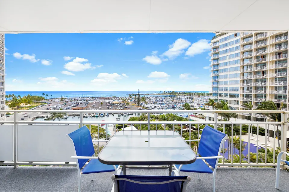 Lanai table and blue chairs overlooking marina and ocean at Ilikai Hotel.