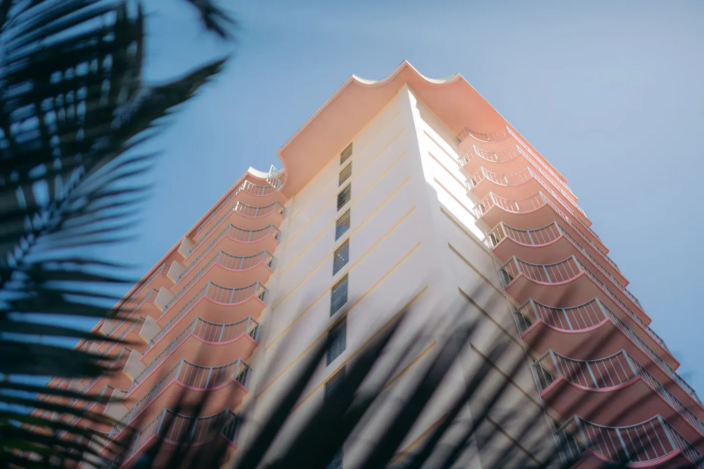 Pink balconies rise above palm fronds on the exterior of Ilima Hotel.