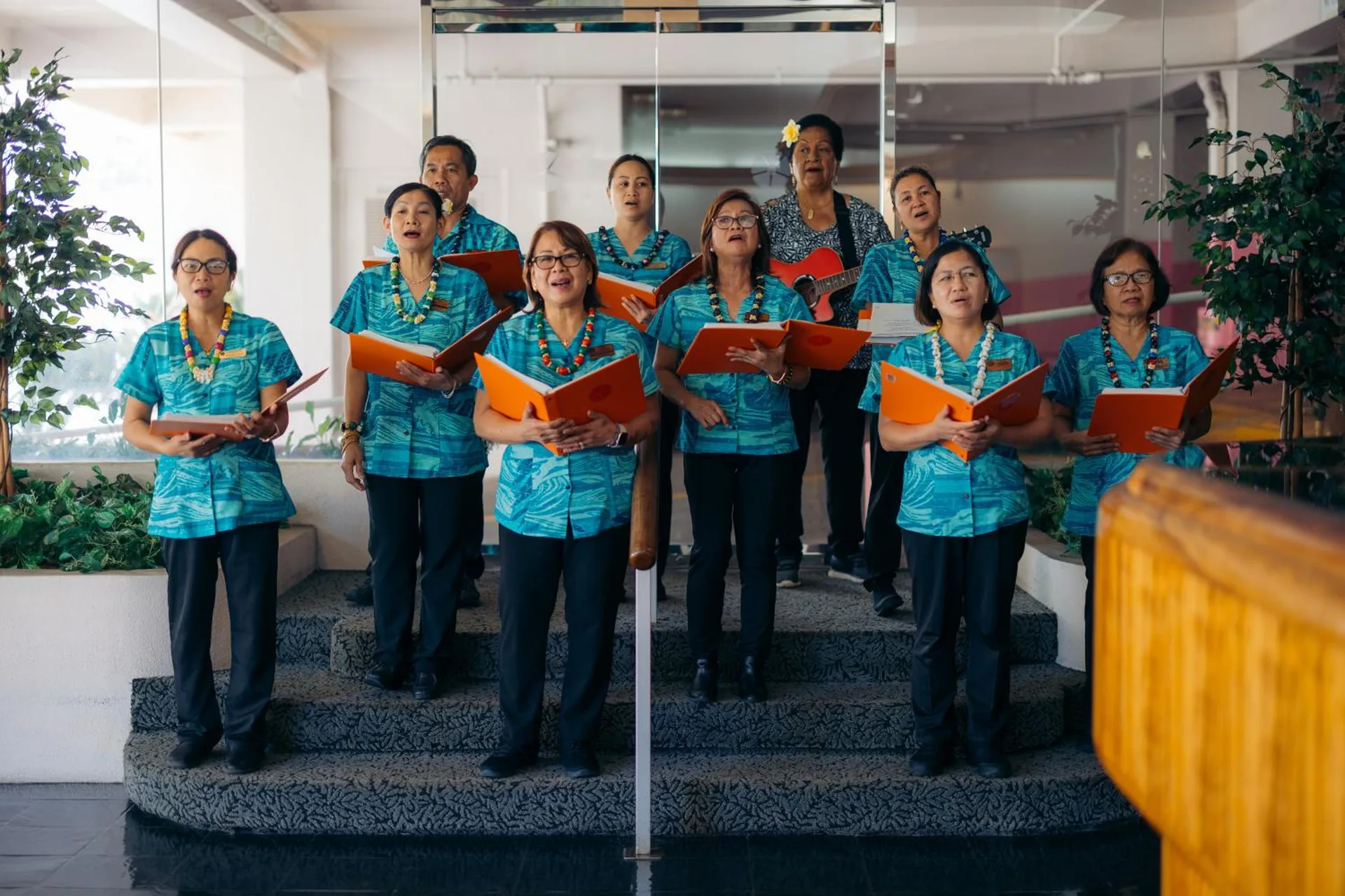 Group of singers holding folders on indoor steps at Ilima Hotel.
