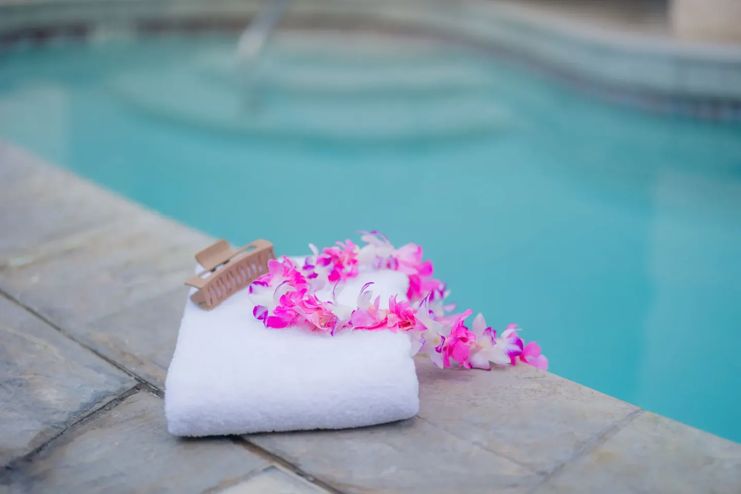 Folded towel with pink flower lei on the pool deck at Ilima Hotel.