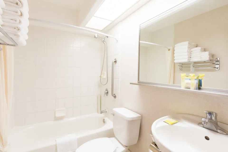 Standard Studio bathroom with tub, sink, mirror, towels, and amenities at Ilima Hotel.