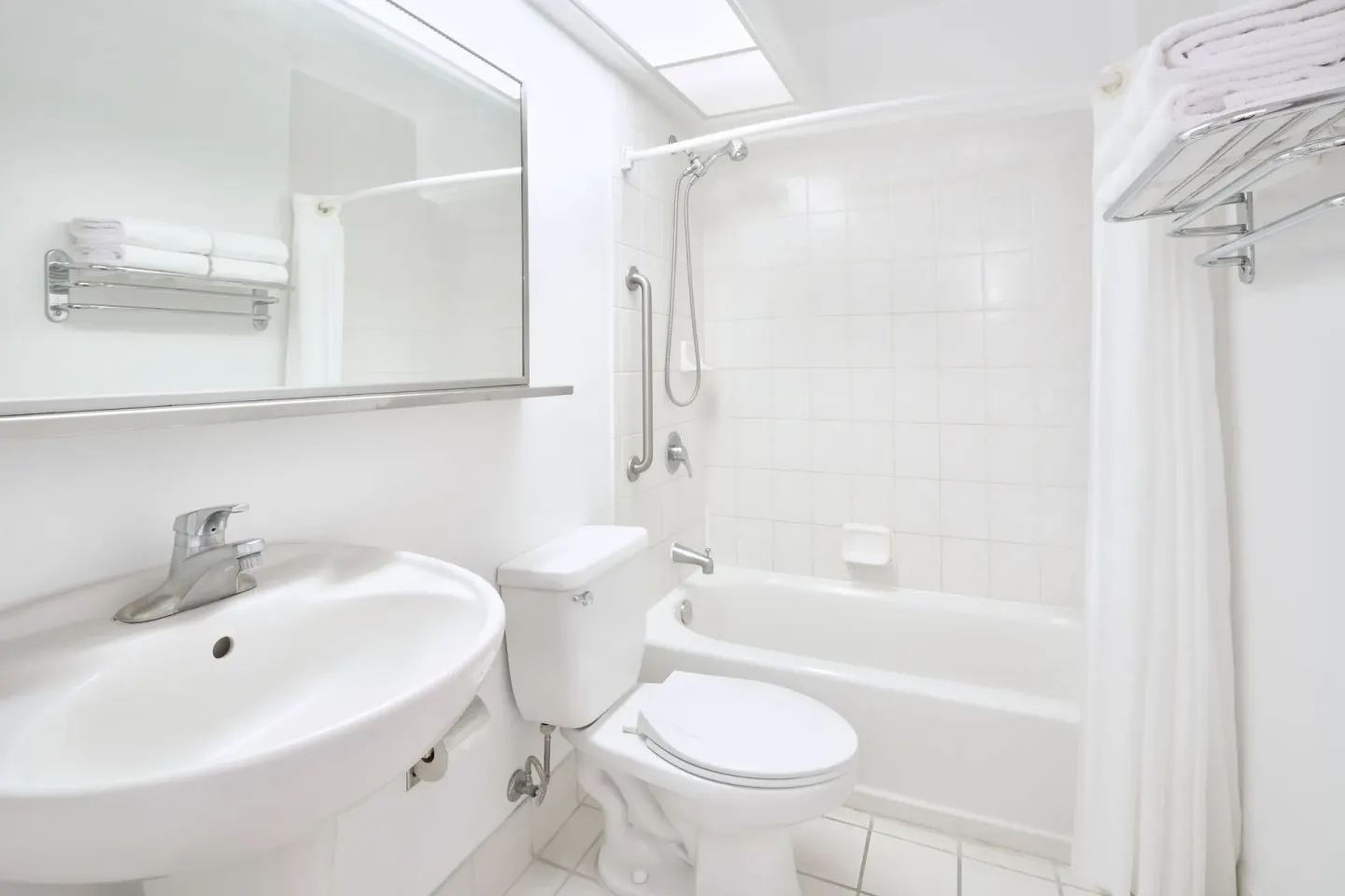 White bathroom with sink, toilet, and tub-shower in a Standard Studio at Ilima Hotel.