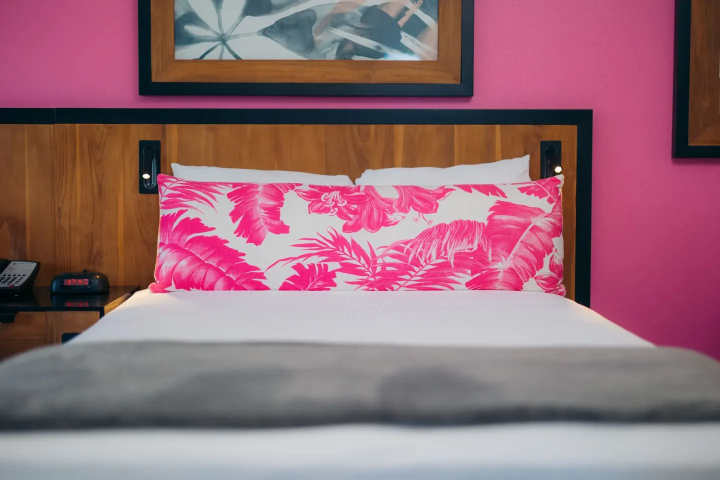 Close-up of a Standard Studio bed with a pink tropical pillow at Ilima Hotel.