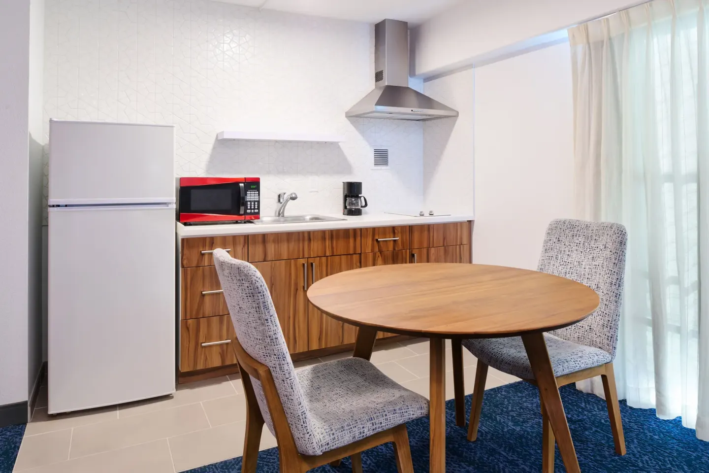 Standard Studio kitchen with dining table, refrigerator, and microwave at Ilima Hotel.