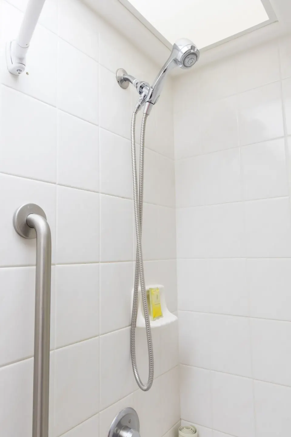 Standard Studio bathroom shower with white tile and grab bar at Ilima Hotel.