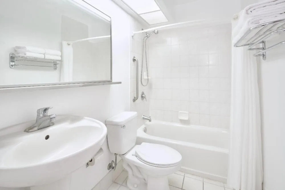 Two Bedroom Suite bathroom with tub, shower, sink, and towels at Ilima Hotel.