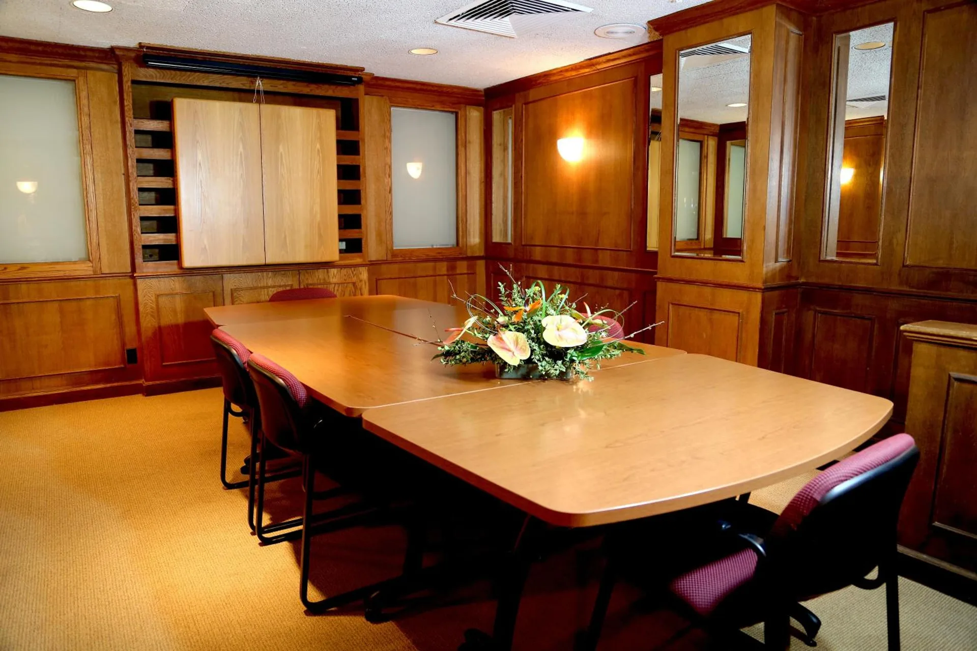 Wood-paneled meeting room with conference table and floral centerpiece at Ilima Hotel.