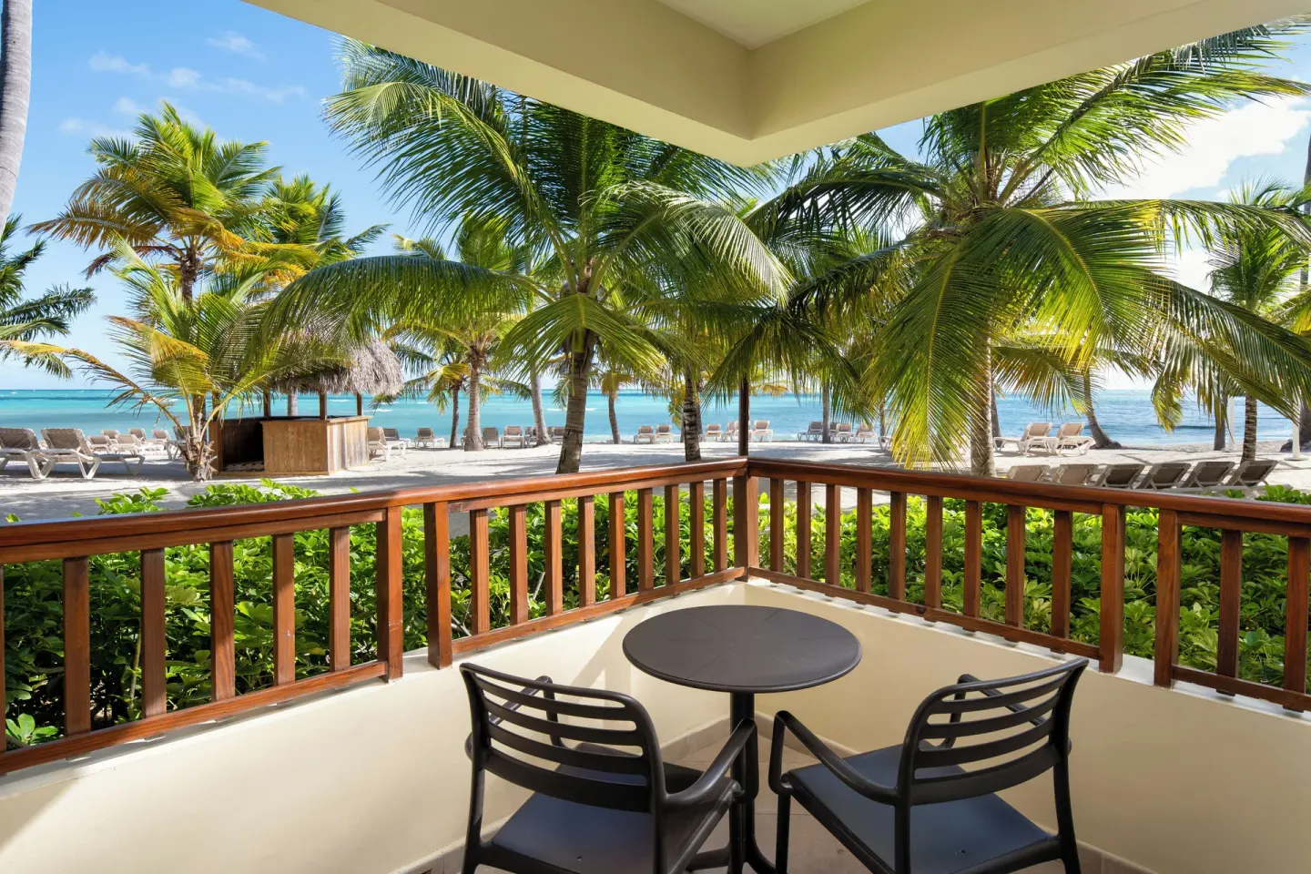 Beachfront balcony with table, chairs, palms, and ocean at Impressive Premium Punta Cana.