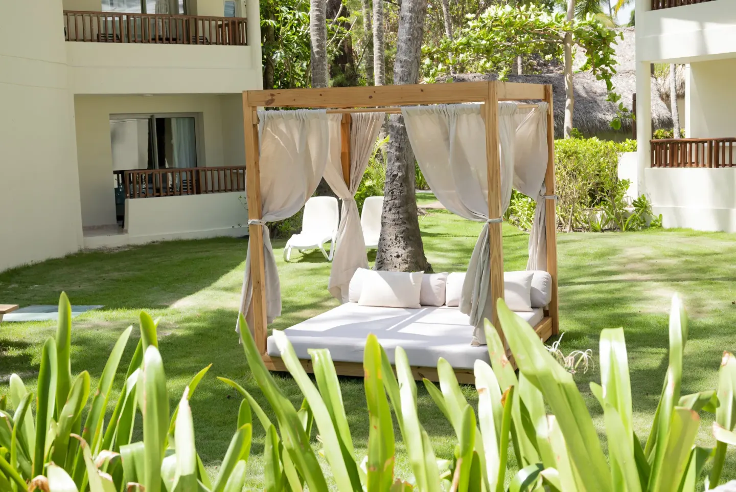 Garden daybed with curtains between guest buildings at Impressive Premium Punta Cana.