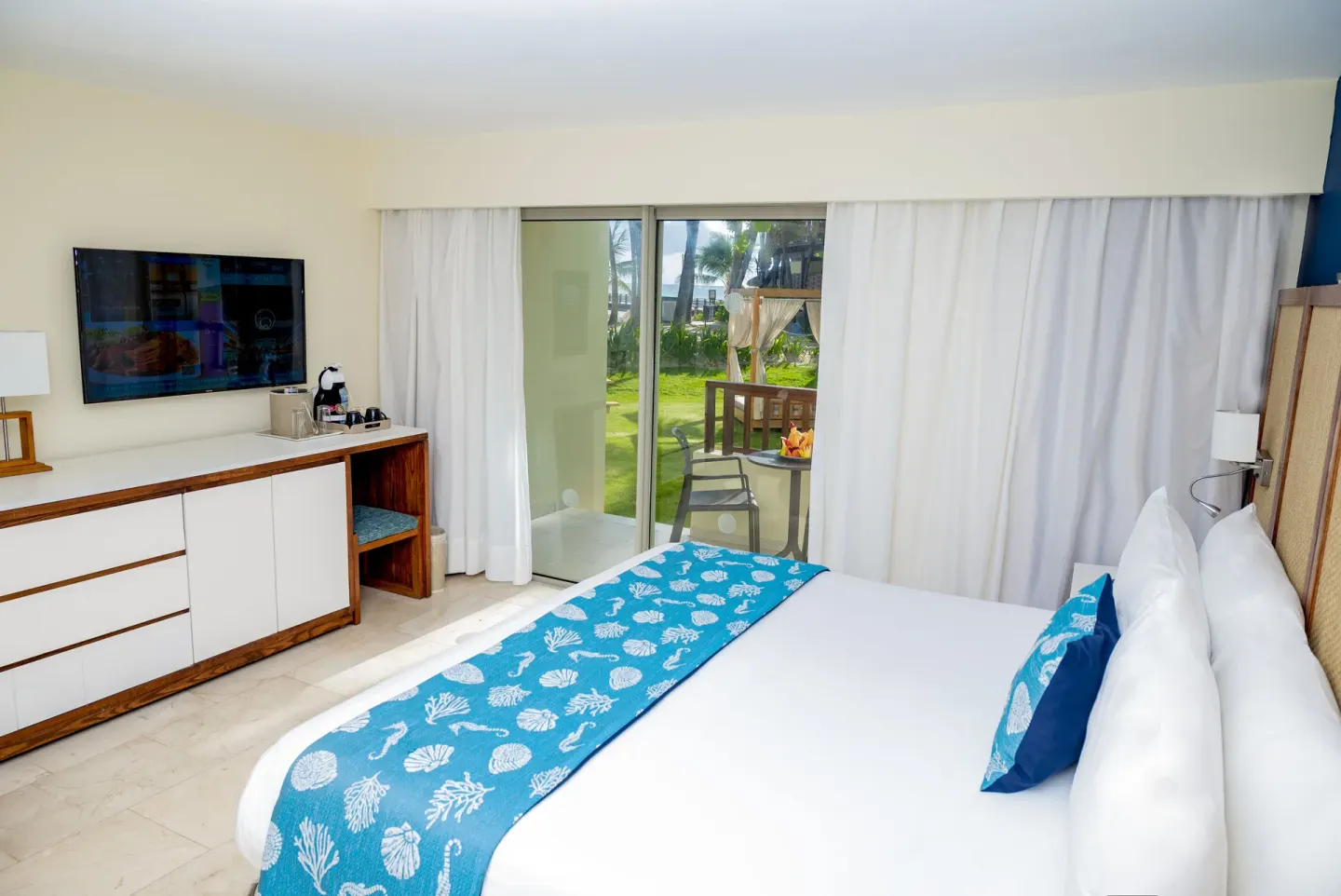 Guest room with king bed, TV cabinet, and patio doors at Impressive Premium Punta Cana.
