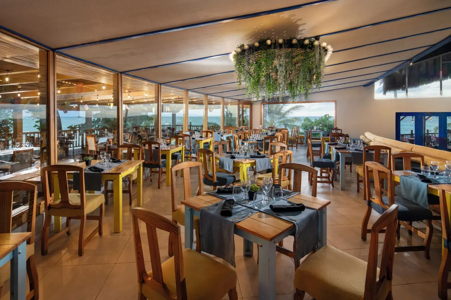 Indoor dining room with wood chairs and ocean-facing windows at Impressive Premium Punta Cana.