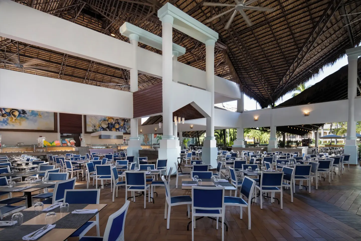 Large open-air dining room with blue chairs at Impressive Premium Punta Cana.