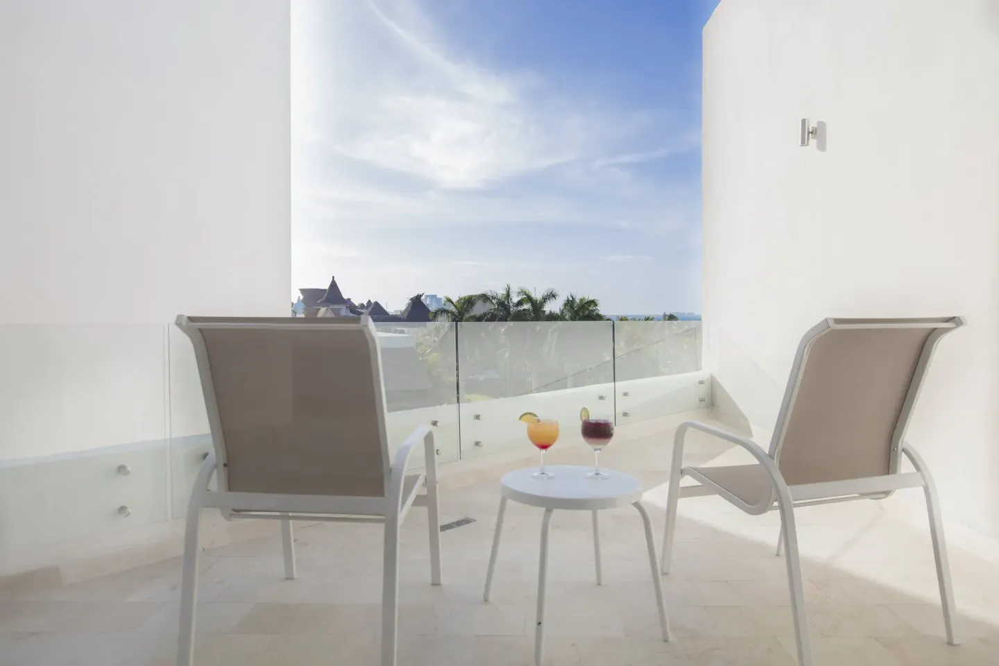 Balcony seating with two drinks and partial sea view at InterContinental Presidente Cancun Resort.