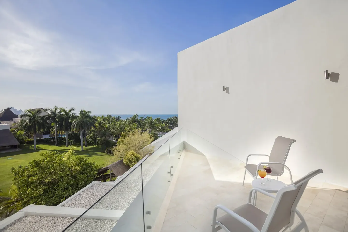 Balcony with chairs, drinks and garden-to-sea view at InterContinental Presidente Cancun Resort.