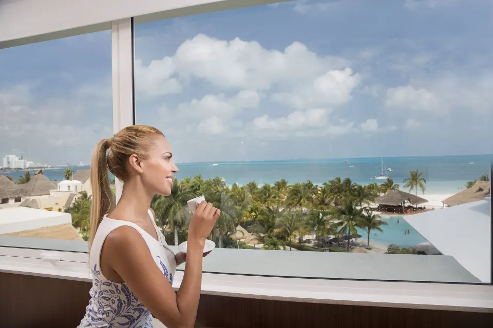 Guest with coffee overlooking the beach and sea at InterContinental Presidente Cancun Resort.