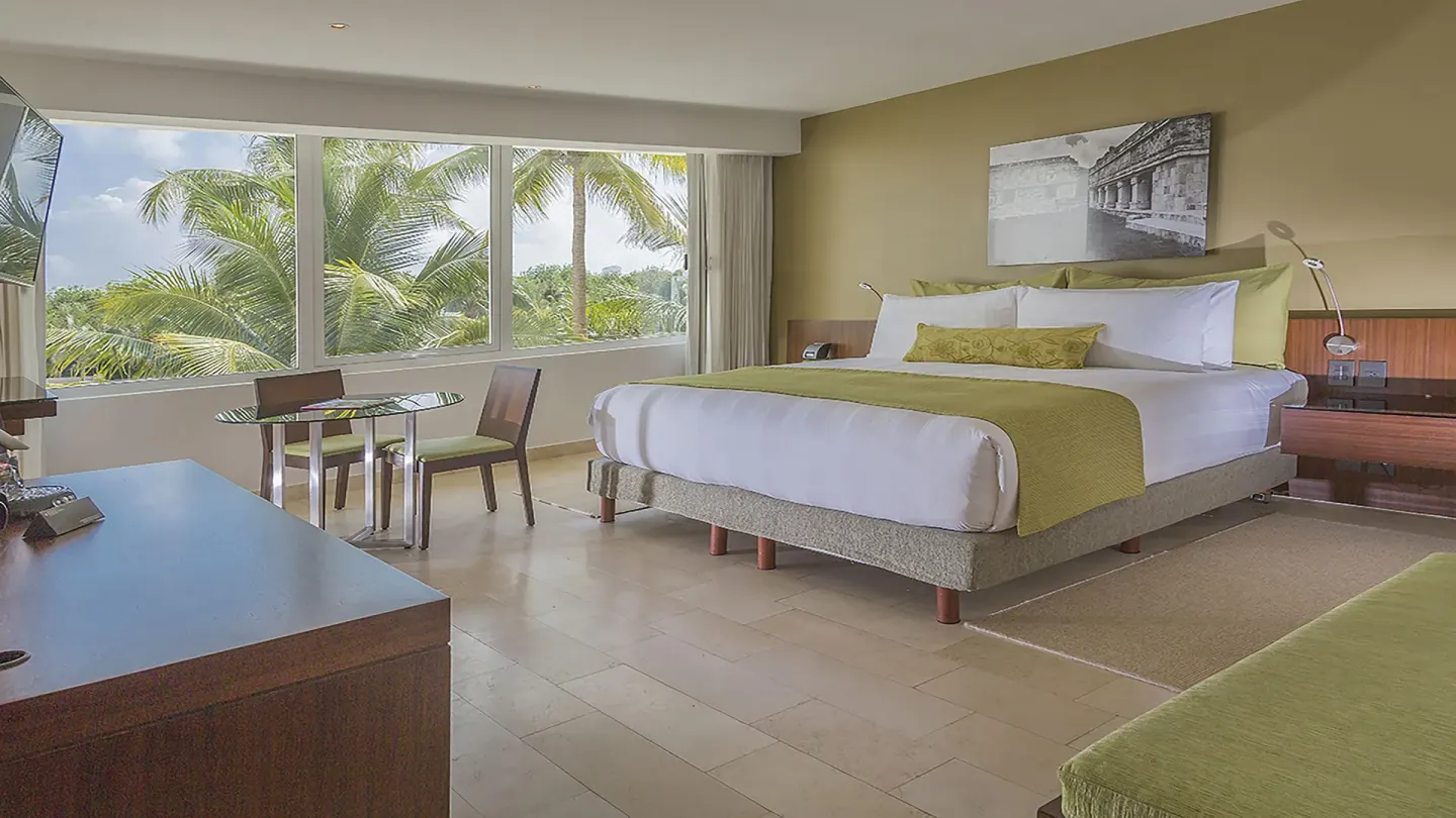King guest room with palm view and dining table at InterContinental Presidente Cancun Resort.