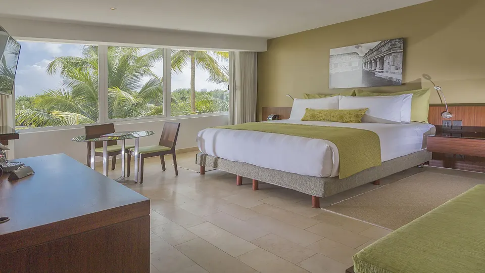 King guest room with palm view and dining table at InterContinental Presidente Cancun Resort.