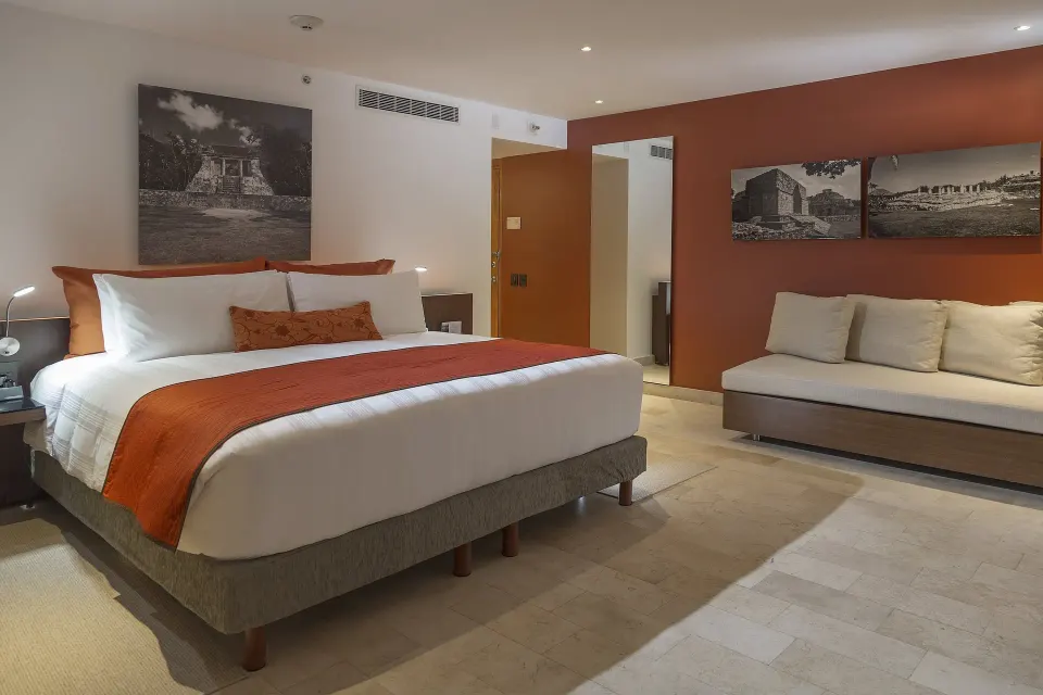 King guest room with sofa and orange accents at InterContinental Presidente Cancun Resort.