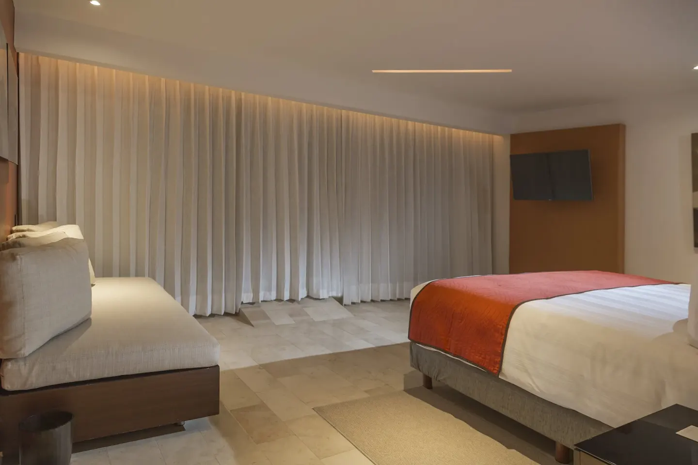 King guest room with chaise lounge and curtained windows at InterContinental Presidente Cancun Resort.