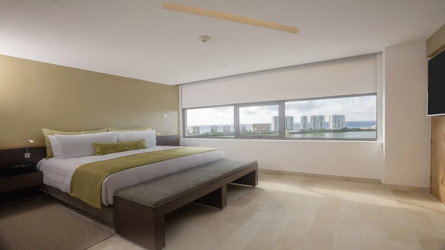 King guest room with long bench and lagoon-view windows at InterContinental Presidente Cancun Resort.