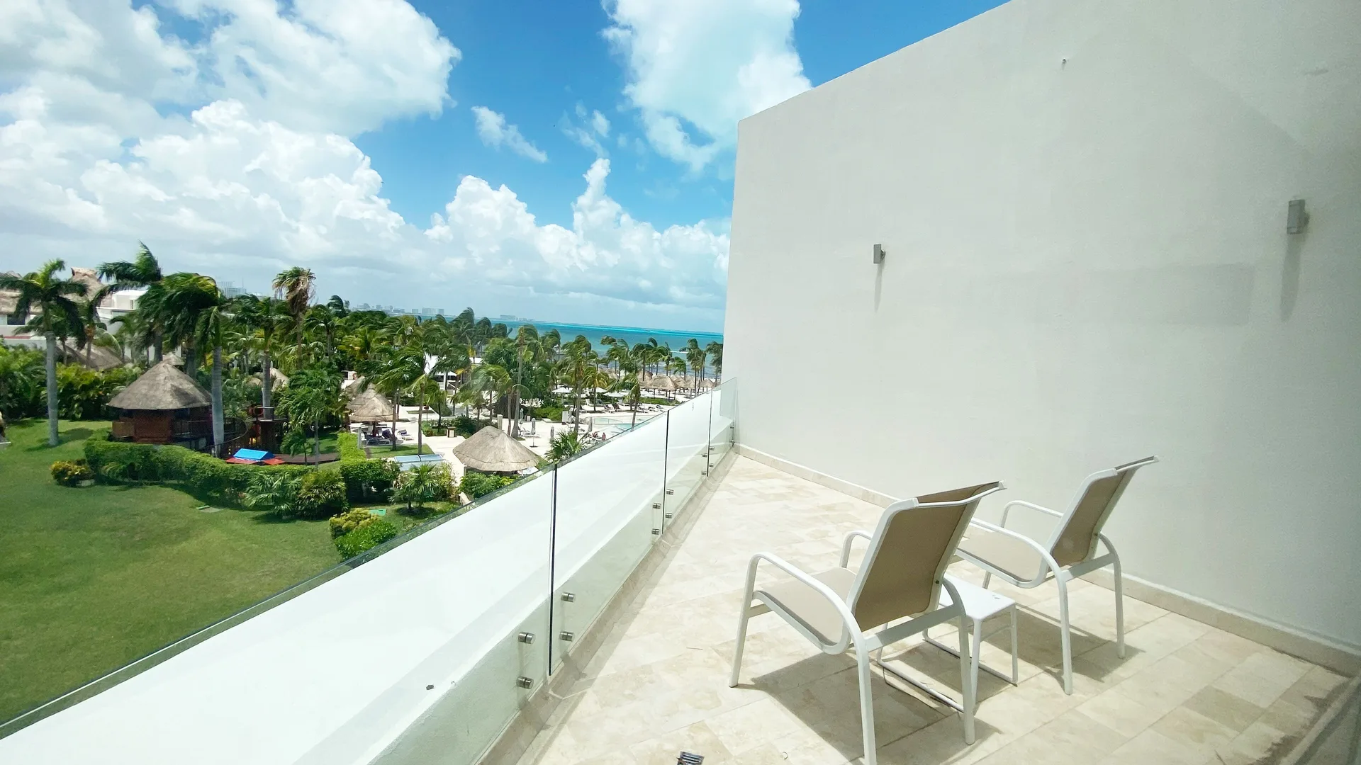 Balcony with two chairs overlooking gardens and sea at InterContinental Presidente Cancun Resort.