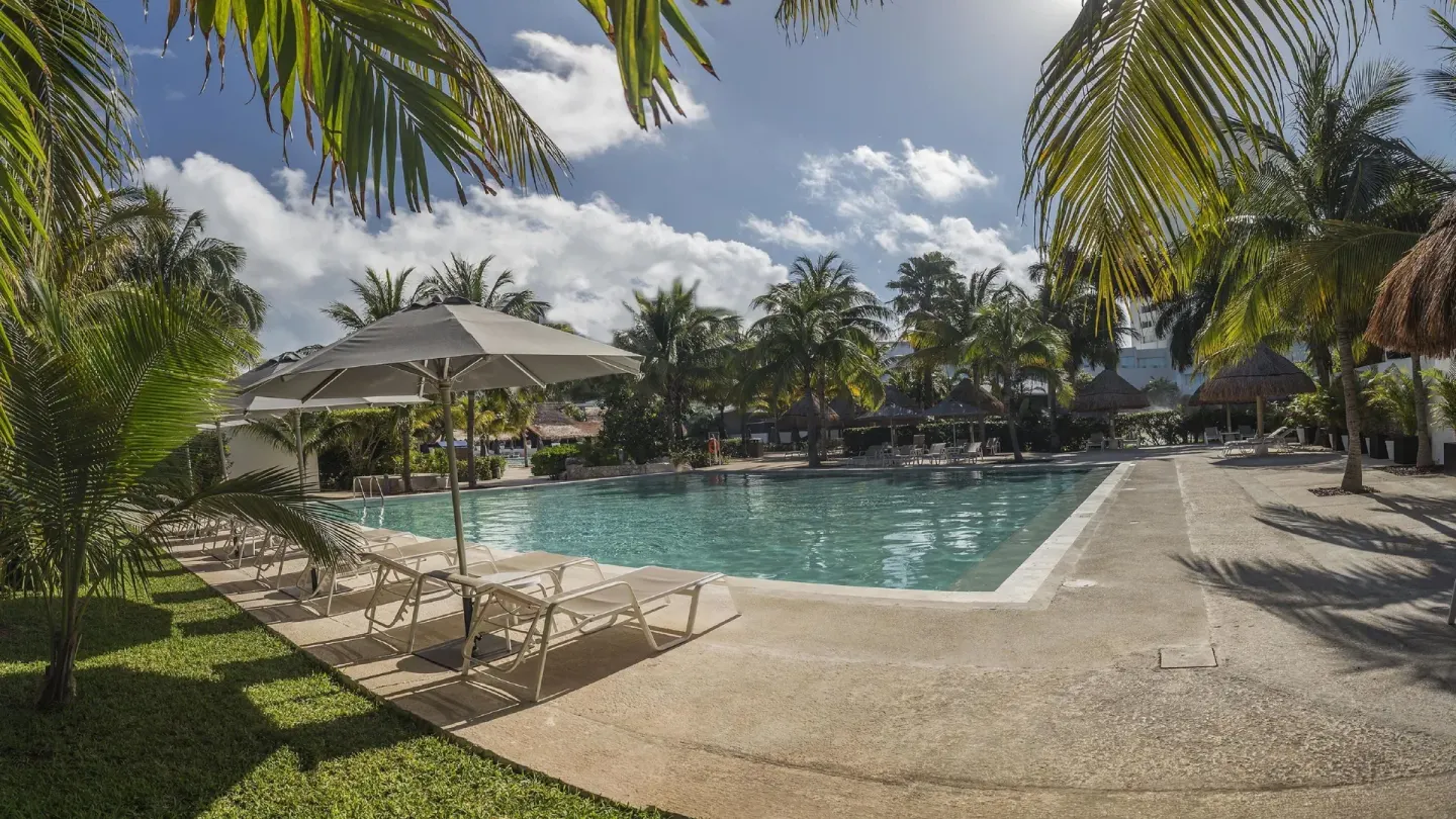 Pool with lounge chairs and palms at InterContinental Presidente Cancun Resort.