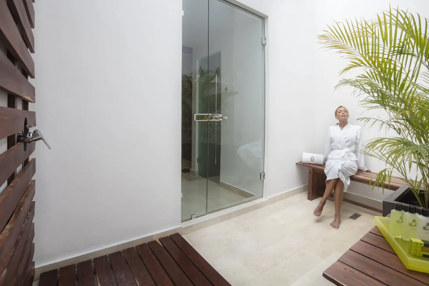 Spa patio with robe-clad guest and glass shower at InterContinental Presidente Cancun Resort.