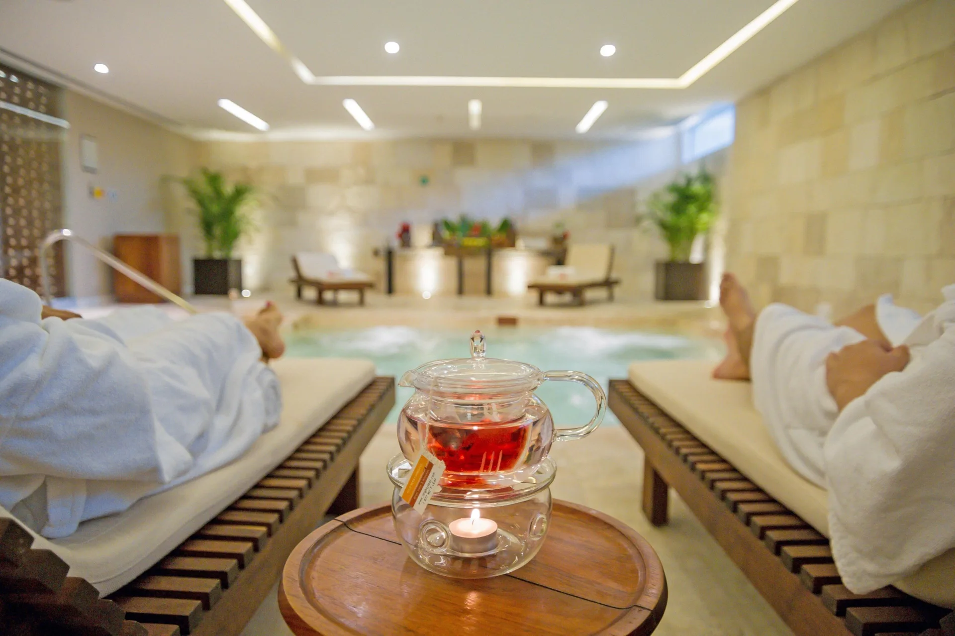 Spa lounge chairs beside an indoor pool with tea service at InterContinental Presidente Cancun Resort.