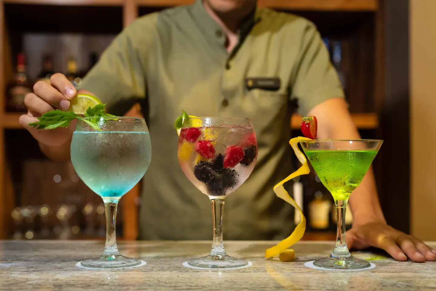 Bartender presenting three colorful cocktails at InterContinental Presidente Cancun Resort.