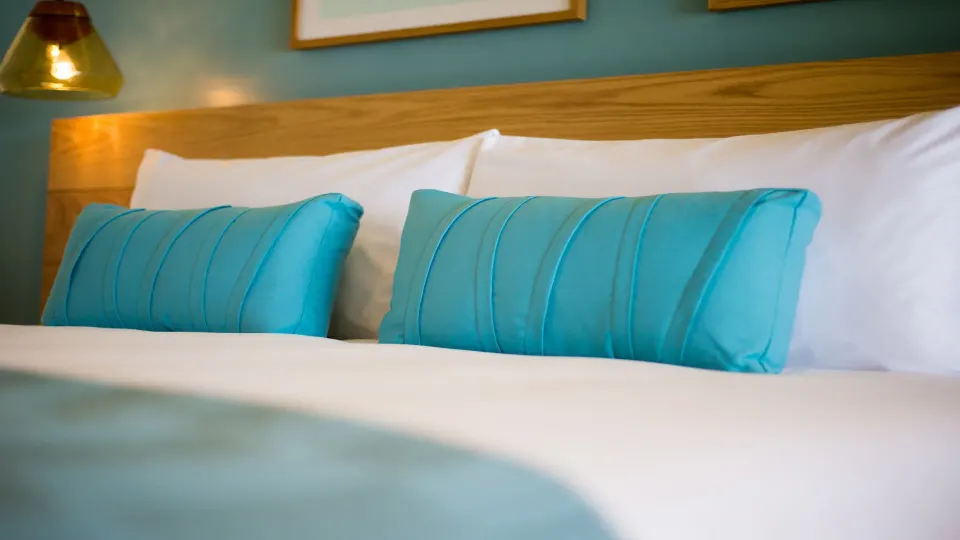 Close-up of turquoise bolster pillows on a hotel bed at InterContinental Presidente Cozumel Resort Spa