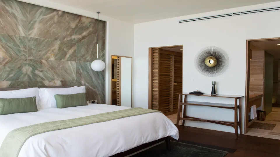 King bed guest room with decorative headboard and open doorway at InterContinental Presidente Cozumel Resort Spa
