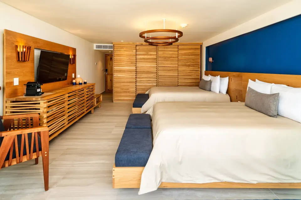 Two beds and media console with blue accent wall in a guest room at InterContinental Presidente Cozumel Resort Spa