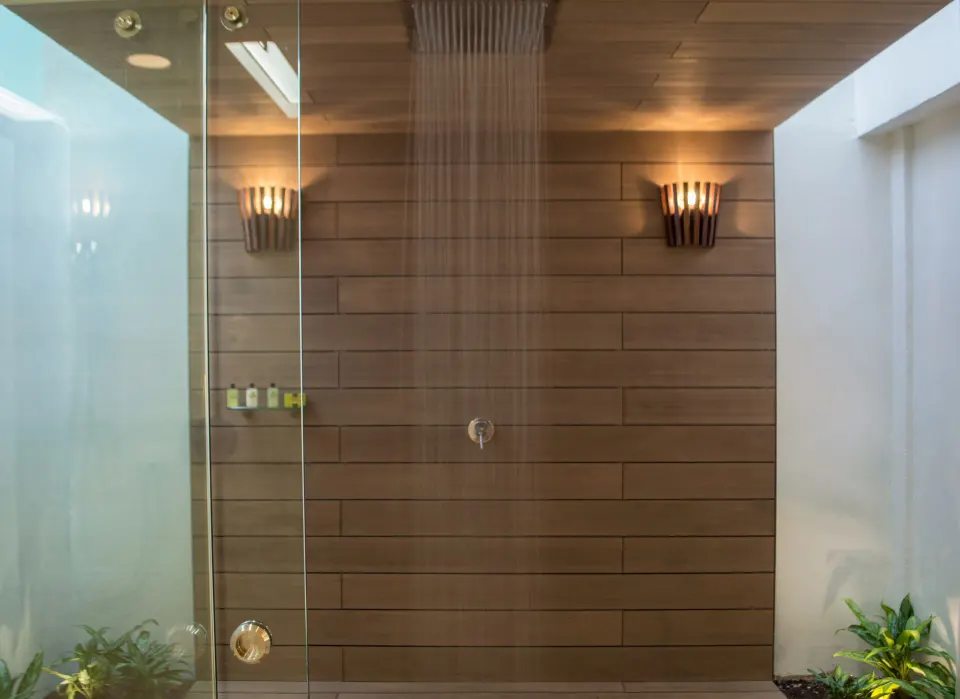 Indoor rain shower with wood-paneled wall and glass door at InterContinental Presidente Cozumel Resort Spa