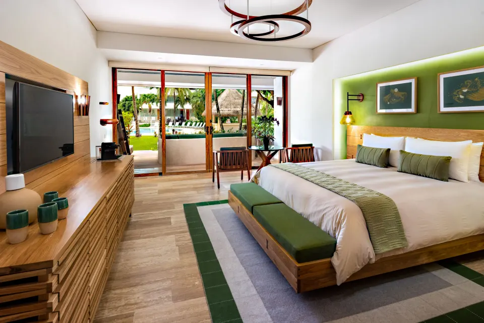 Spacious guest room with king bed, teal accents, and balcony overlooking palm trees at InterContinental Presidente Cozumel Re