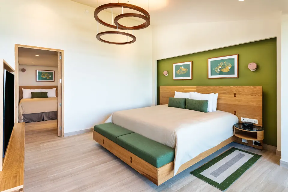 King bed with green accent wall and bedside seating at InterContinental Presidente Cozumel Resort Spa