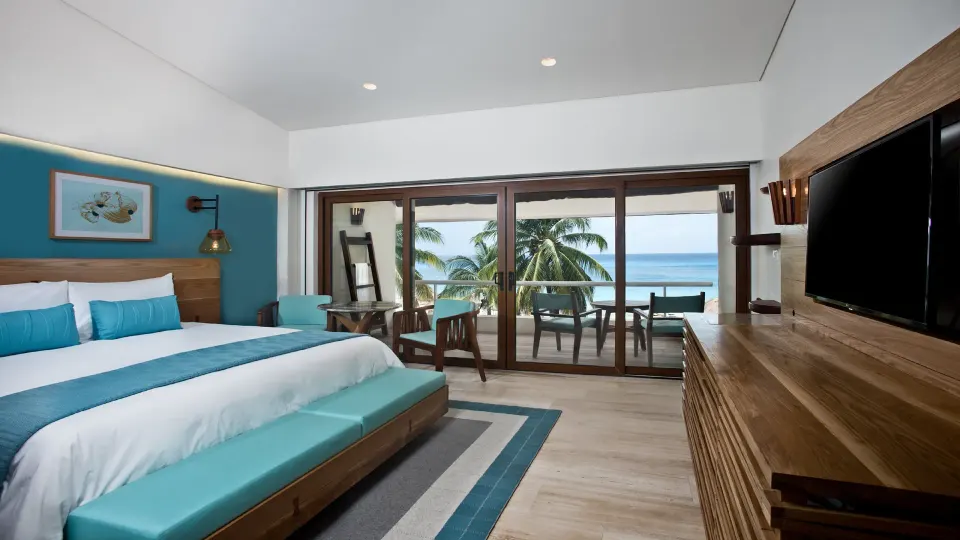 Guest room with king bed, turquoise accents and balcony overlooking ocean at InterContinental Presidente Cozumel Resort Spa