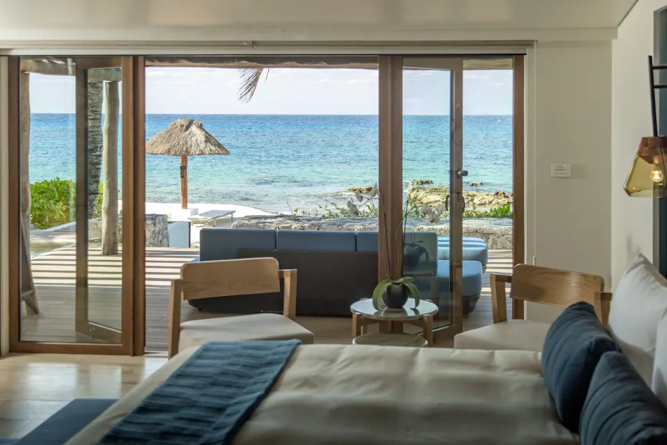 Bed foreground with sliding doors opening to sea and palapa umbrella at InterContinental Presidente Cozumel Resort Spa