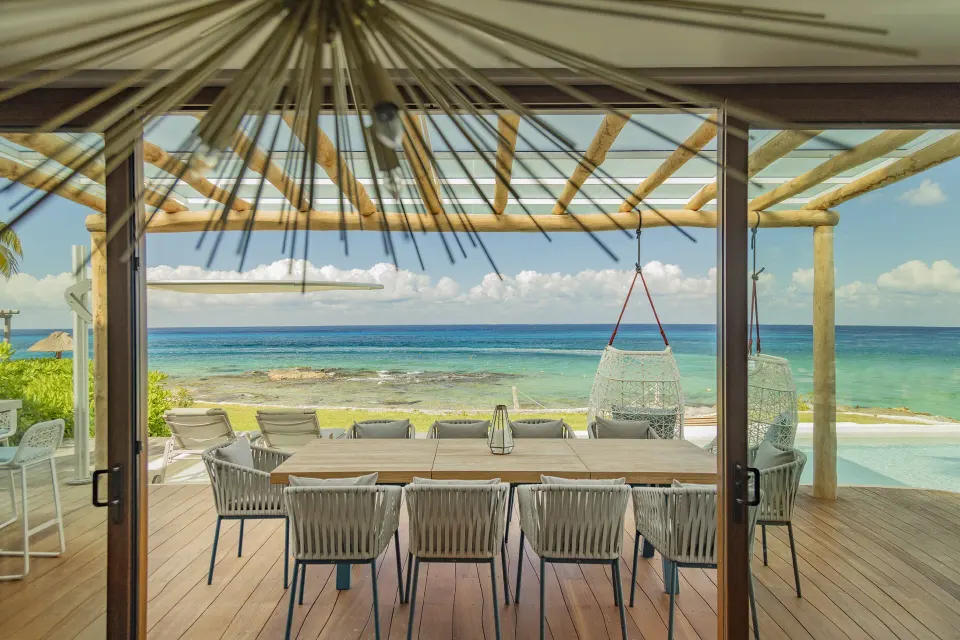 Oceanfront dining terrace with long table and hanging chairs at InterContinental Presidente Cozumel Resort Spa