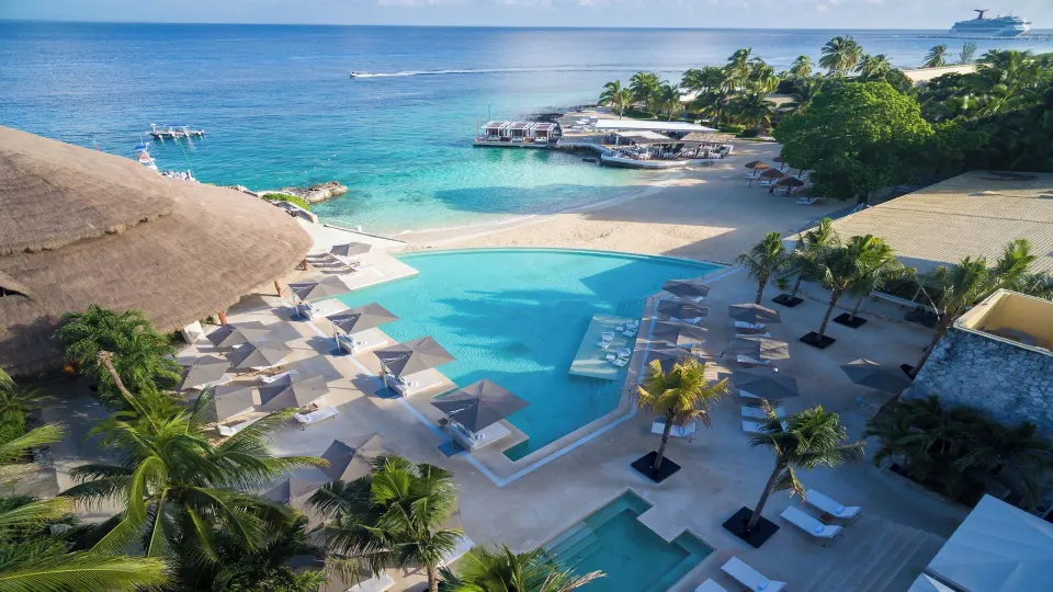 Elevated view of the resort pool deck, cabanas, and adjacent ocean at InterContinental Presidente Cozumel Resort Spa