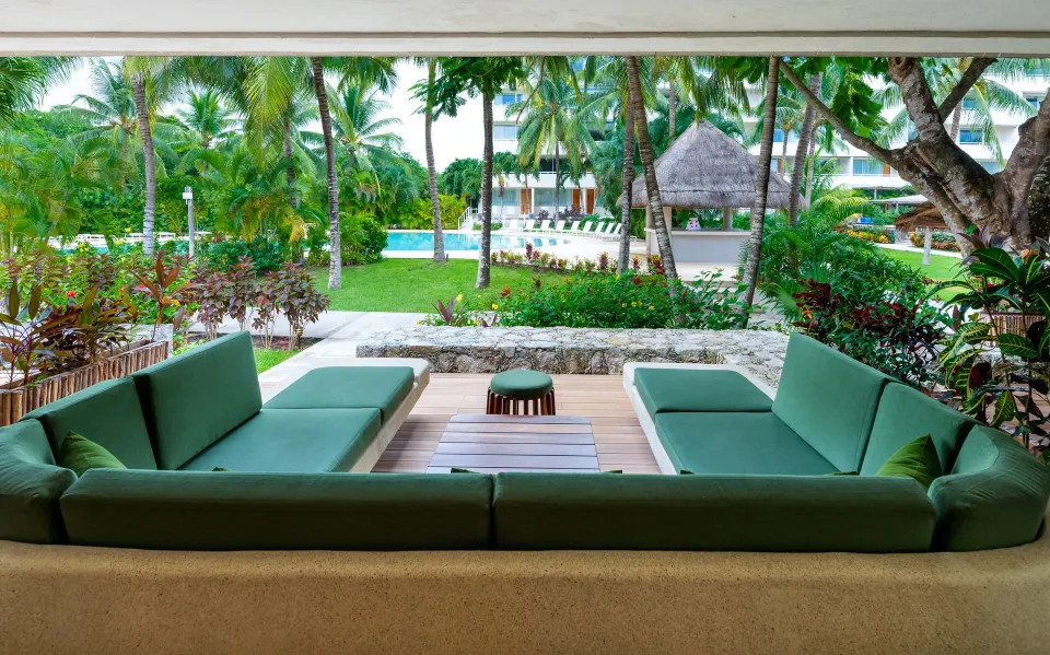 Resort grounds with pool, palm trees and thatched palapa at InterContinental Presidente Cozumel Resort Spa