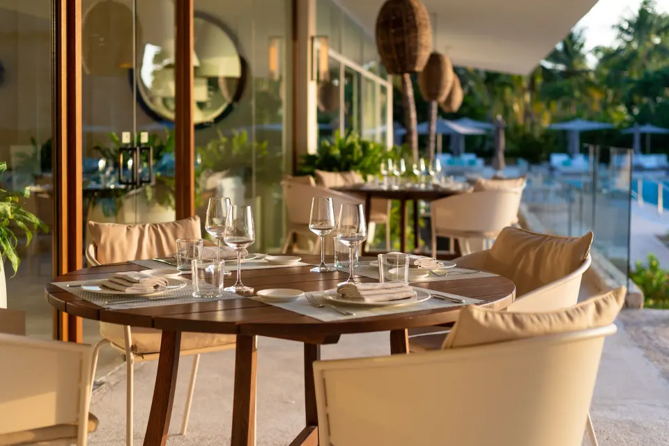 Round dining table with cushioned chairs next to pool at InterContinental Presidente Cozumel Resort Spa