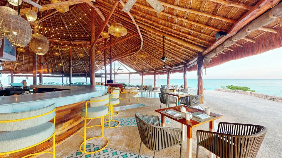 Oceanfront palapa bar and dining area with wicker chairs at InterContinental Presidente Cozumel Resort Spa