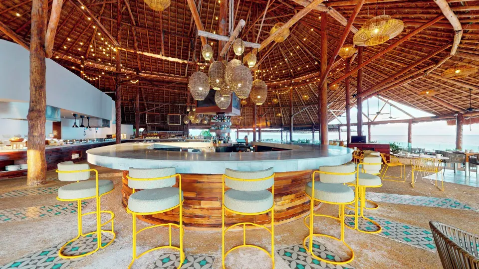 Circular palapa bar with yellow stools at InterContinental Presidente Cozumel Resort Spa