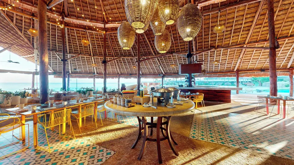 Large thatched-roof palapa restaurant interior with buffet table at InterContinental Presidente Cozumel Resort Spa